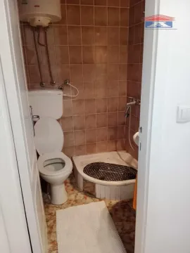Manje kupatilo sa tuš kabinom i WC šoljom obloženo smeđim pločicama. - image 6