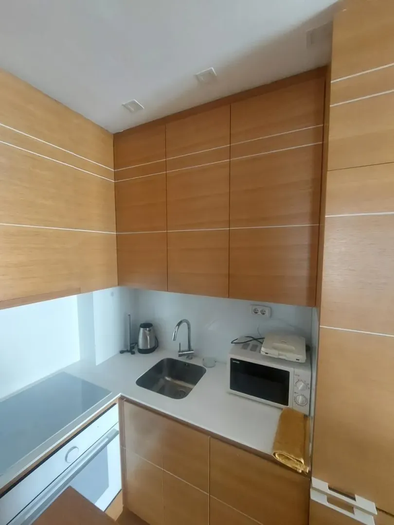 Small wooden kitchen with a built-in sink and appliances.