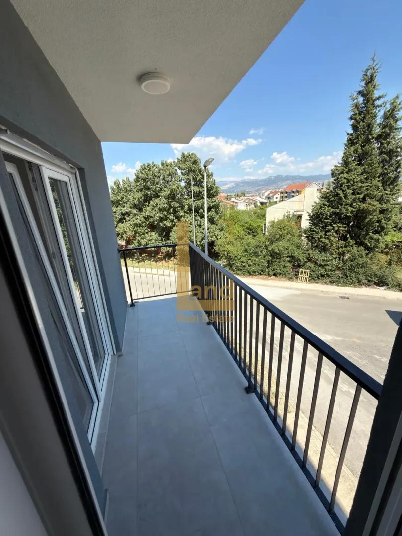 Nenamješten balkon sa pogledom na ulicu i zelenilo.