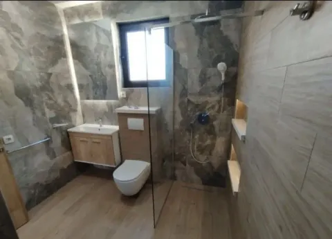 Modern bathroom with a walk-in shower, washbasin, and toilet. - image 5