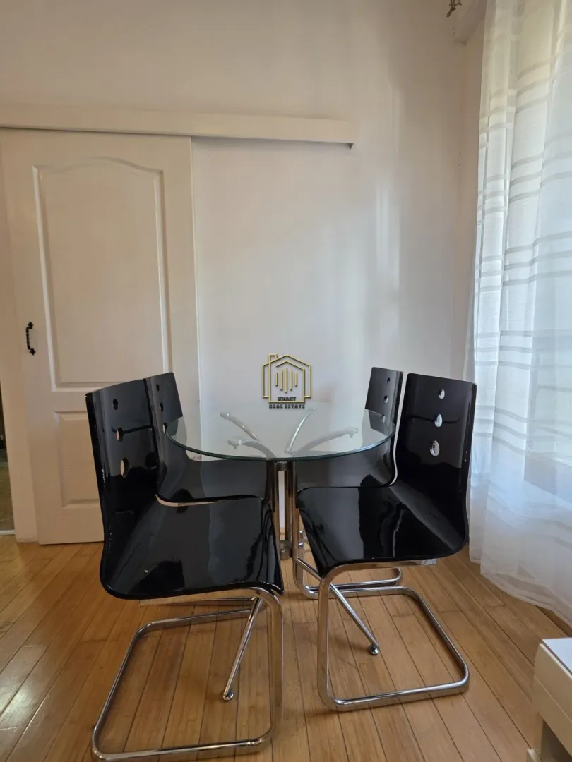 Dining table with four black chairs in the corner of the room near the window.