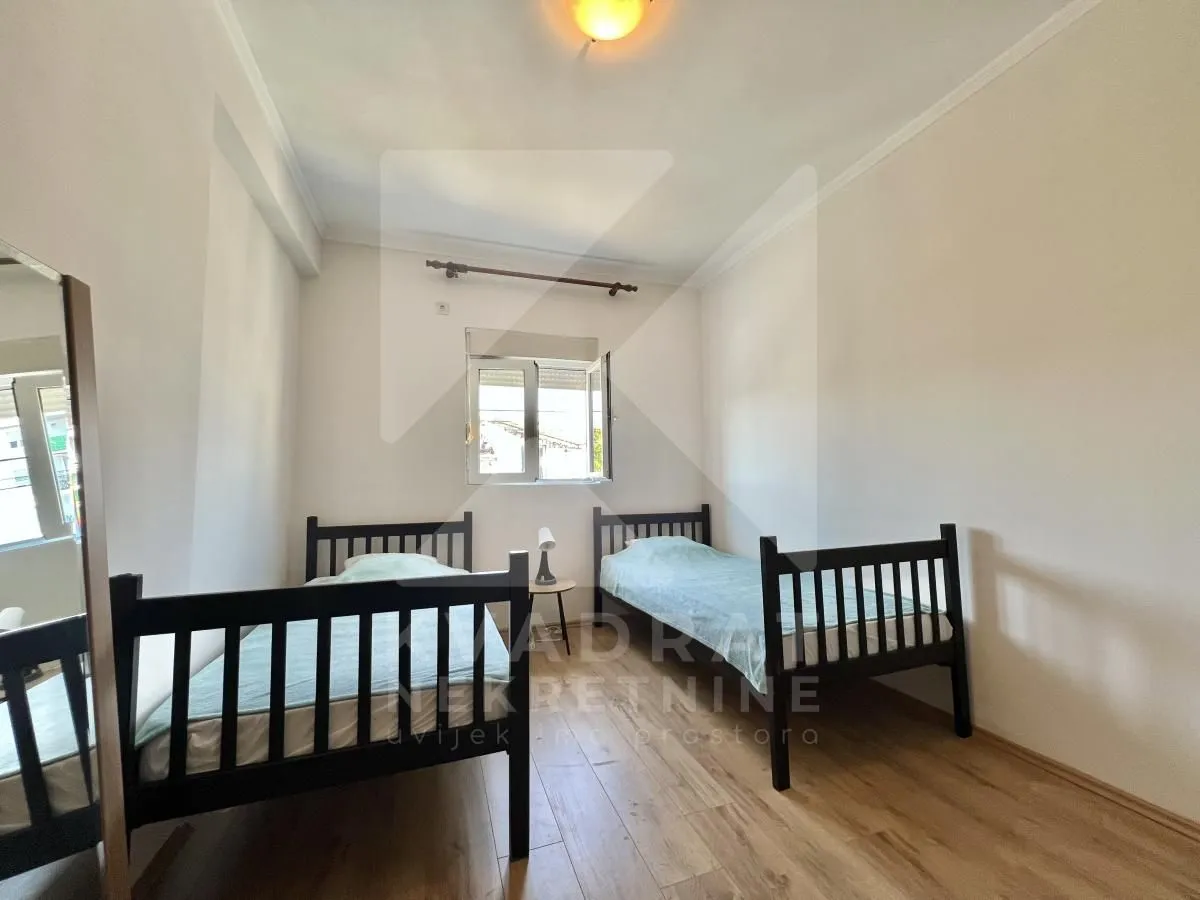Bedroom with two wooden beds and a window.