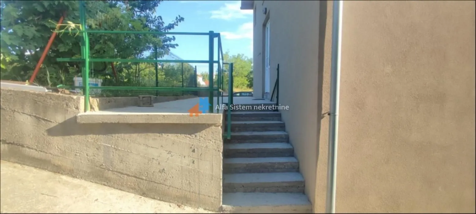 Exterior view of the stairs and entrance to the building with a yard.