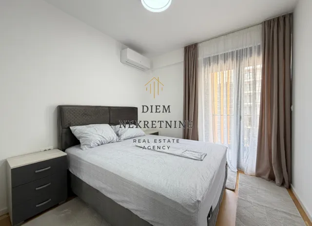 Furnished bedroom with a double bed, nightstand, and balcony access.