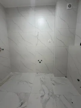 Novije opremljeno kupatilo sa bijelim mermernim pločicama i pripremljenim priključcima za sanitarije. - image 9
