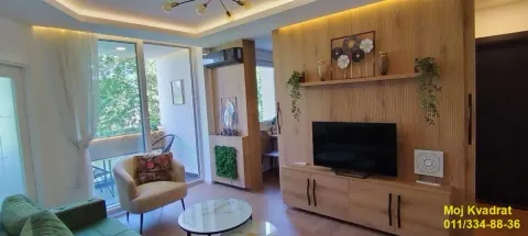 Dnevni boravak sa garniturom, drvenim zidnim panelima i televizorom. - image 2
