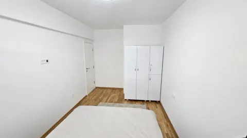 Manja spavaća soba sa krevetom, bijelim garderoberom i drvenim podom. - image 7