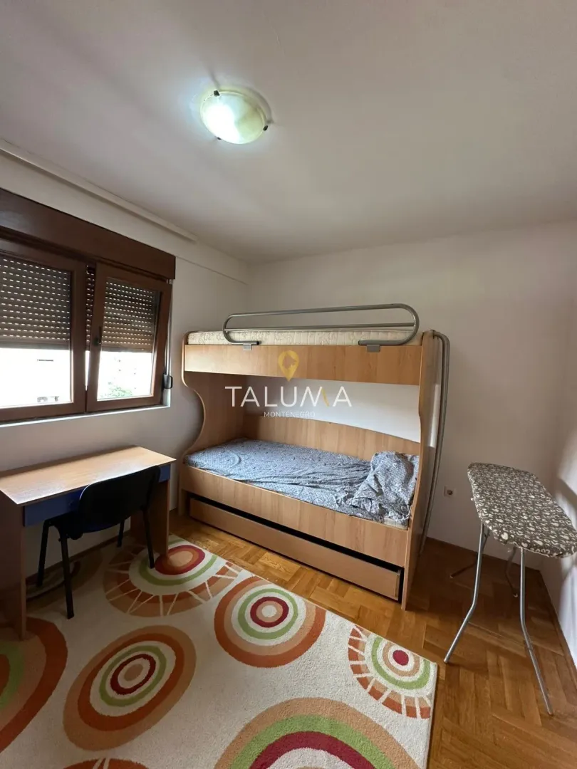 Children's room with a bunk bed, a desk, and a rug with colorful circular patterns.