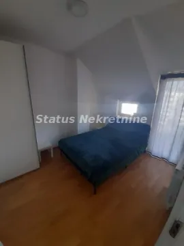 Nameštena spavaća soba sa bračnim krevetom, ormarom i kosim plafonom. - image 4