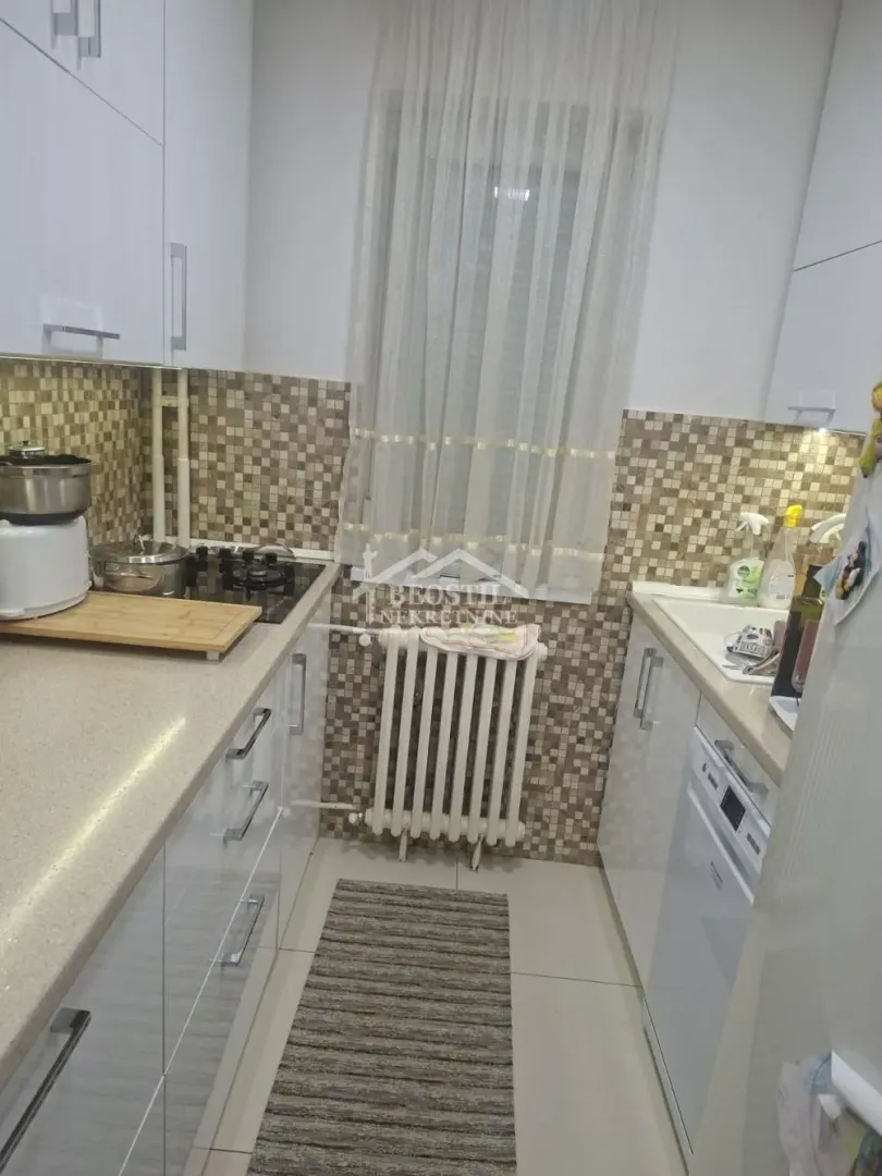 Small kitchen with white cabinets and a window.