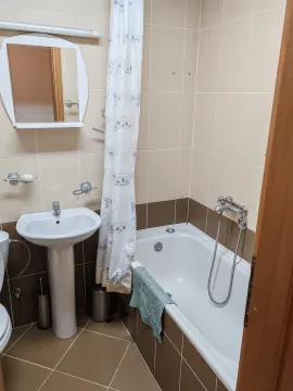 Small bathroom with a bathtub, washbasin, and mirror. - image 6