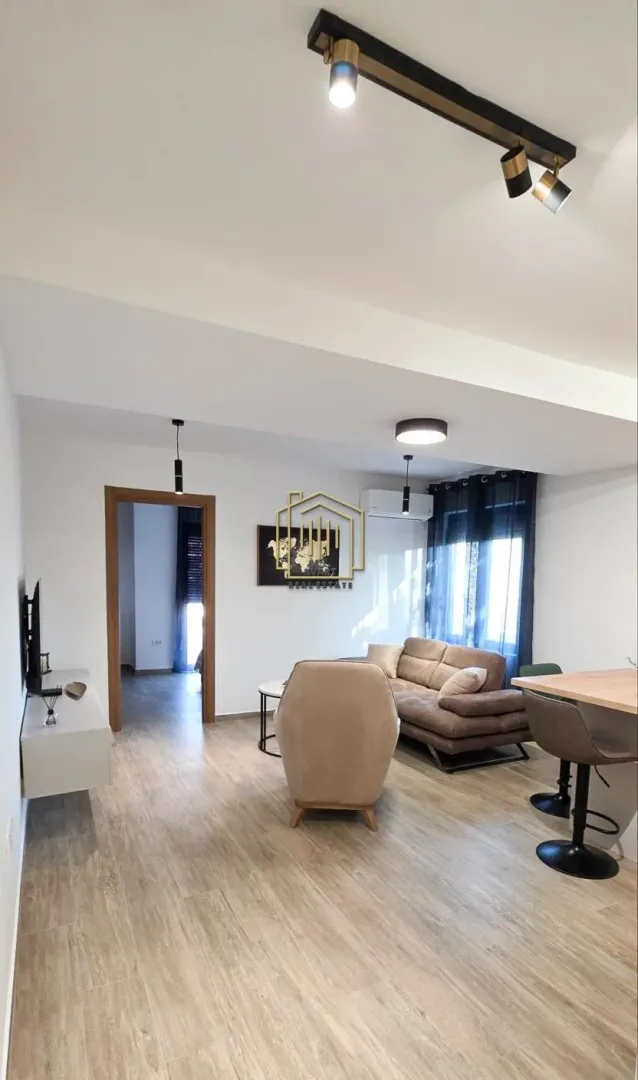 Living room with sofa, TV unit, and dining table.