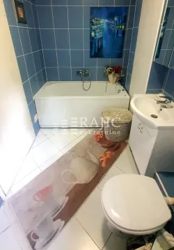 Smaller bathroom with a bathtub, washbasin, and toilet. - image 12