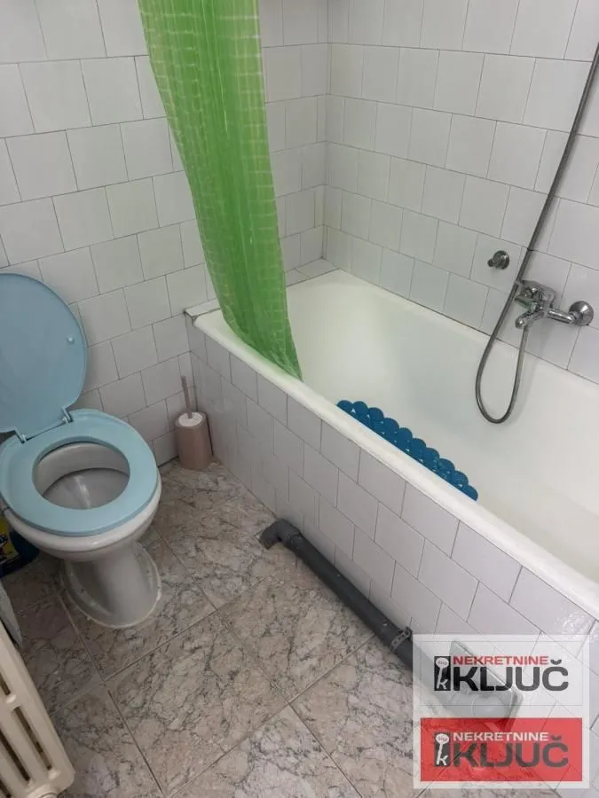 Kupatilo sa kadom, toaletom i belim zidnim pločicama.