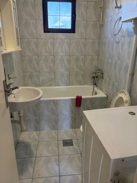 Manje kupatilo obloženo keramičkim pločicama sa kadom, umivaonikom i veš mašinom. - image 6