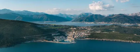 Pogled iz vazduha na primorsko naselje sa marinom i planinama u pozadini. - image 4