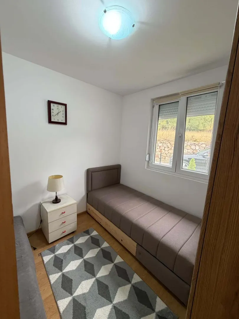 Smaller bedroom with a pull-out bed, nightstand, and window.