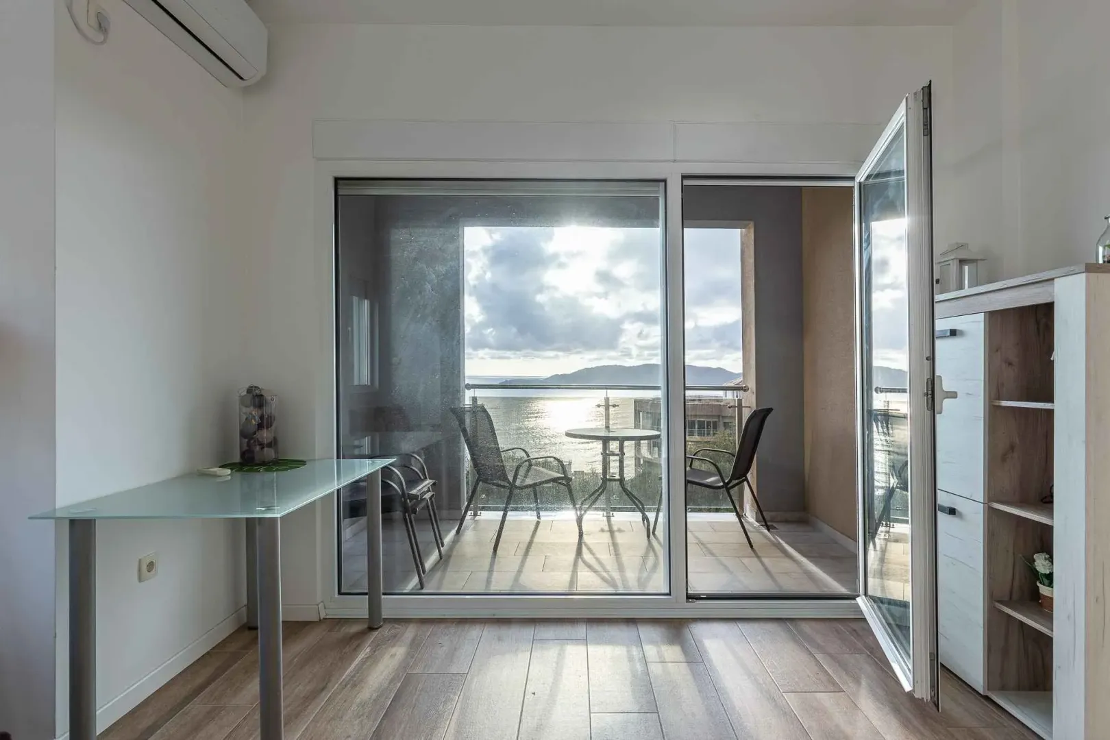 View of the terrace and the sea through an open balcony door.
