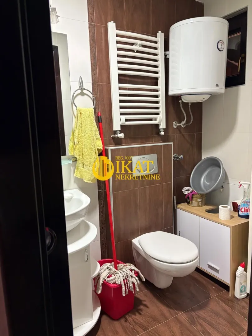 Manje kupatilo sa WC šoljom, umivaonikom, bojlerom i radijatorom za peškire.
