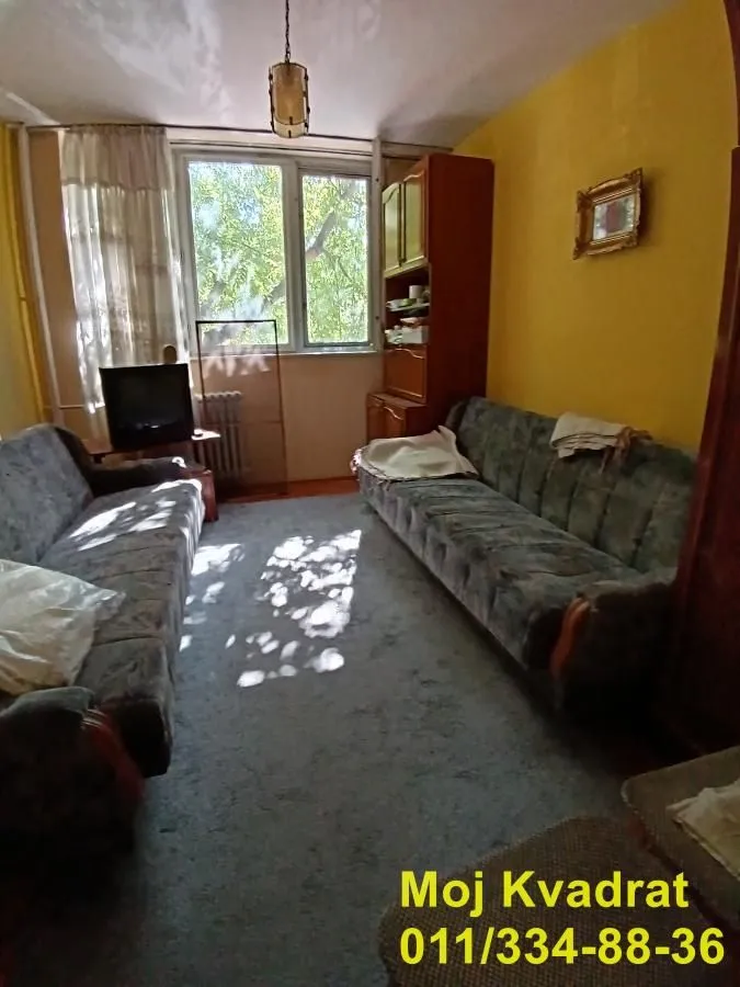 Dnevna soba sa sofama, drvenim ormanom i prozorom.