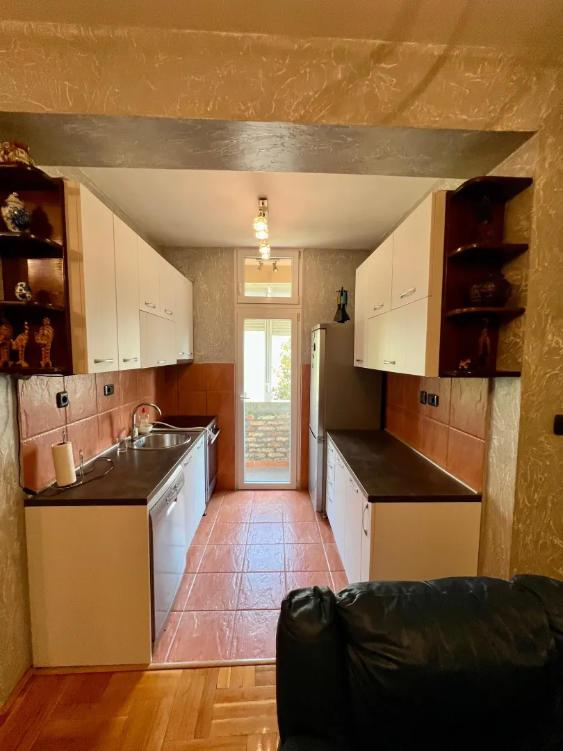 Narrow kitchen with white cabinets and access to the terrace.