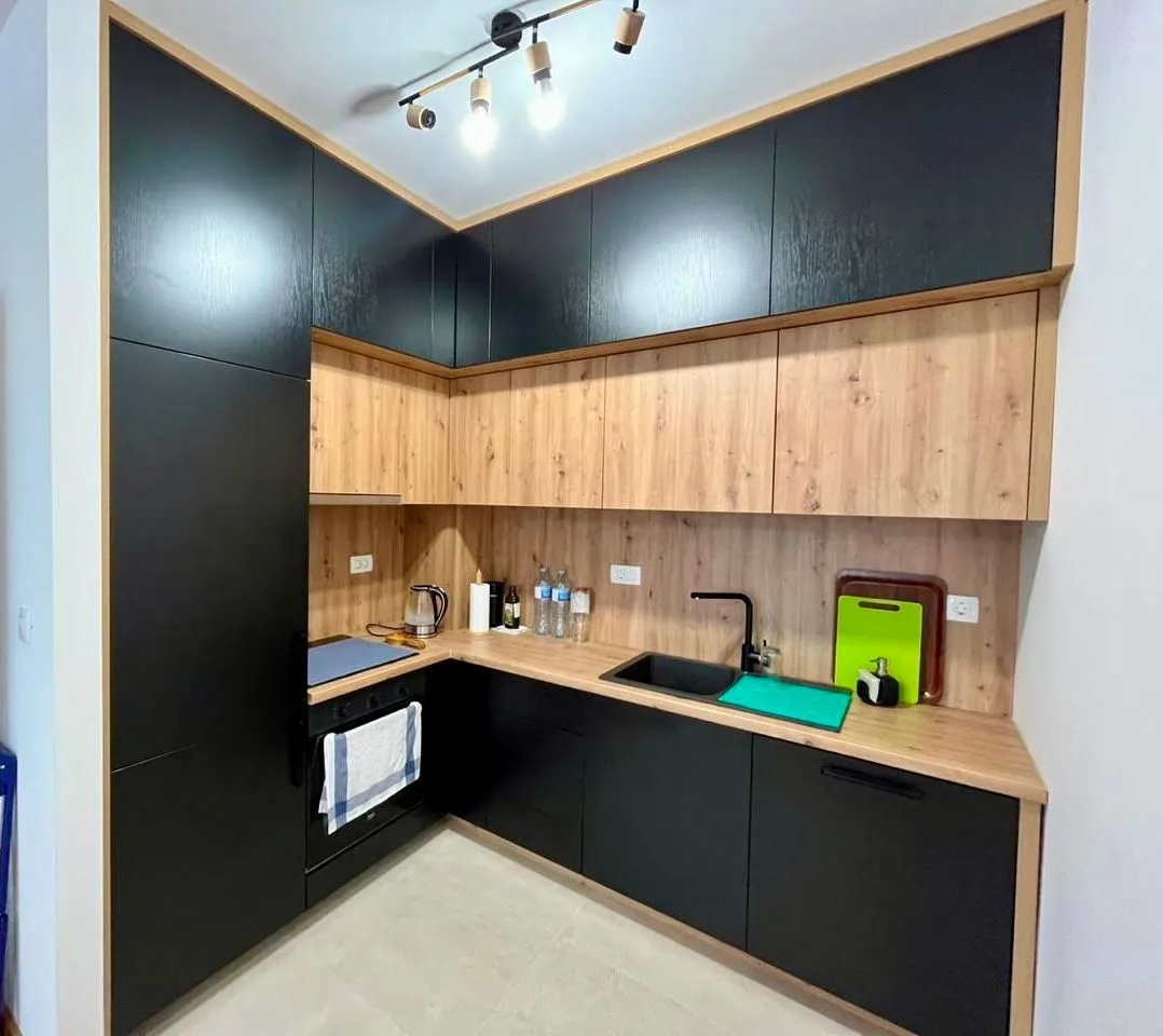 Modern corner kitchen with black units and wooden accents.