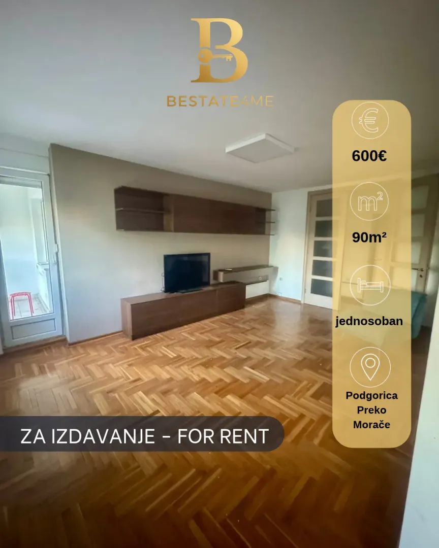 Prazna dnevna soba sa parketom i TV komodom.