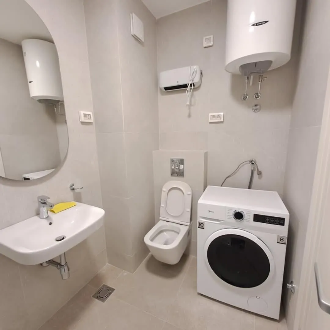 Moderne kupatilo sa umivaonikom, WC šoljom, veš mašinom i bojlerom.