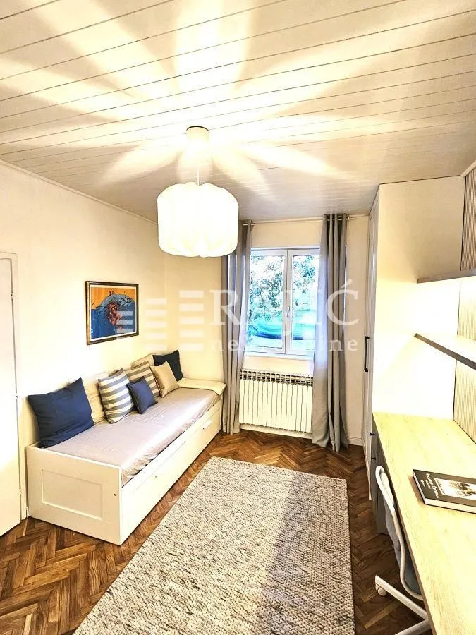 Small room with a bed, desk, and parquet flooring.