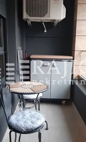 Smaller balcony with a table, chairs, and a cabinet.