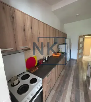 Kuhinja sa drvenim elementima, tamnom radnom pločom i šporetom. - image 4
