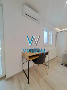 Dnevna soba sa radnim stolom i klima uređajem na zidu. - image 10