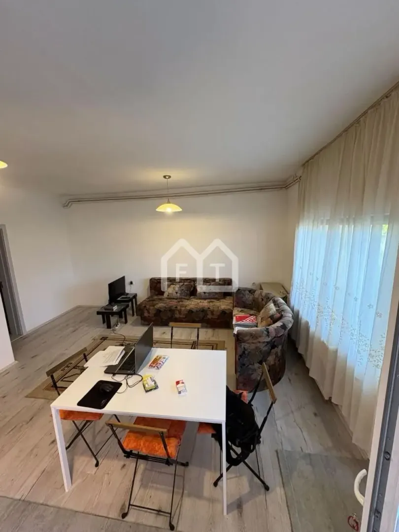 Living room with a sofa set, dining table, and curtained windows.