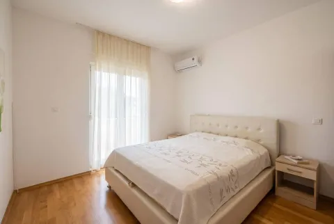 Svjetla spavaća soba sa bračnim krevetom, drvenim podom i izlazom na balkon. - image 8