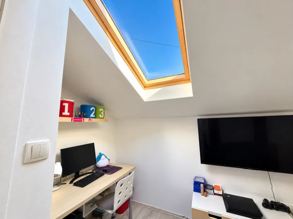 Attic room with a desk and a skylight.