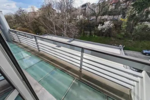 View from the balcony overlooking the surrounding greenery and street. - image 3
