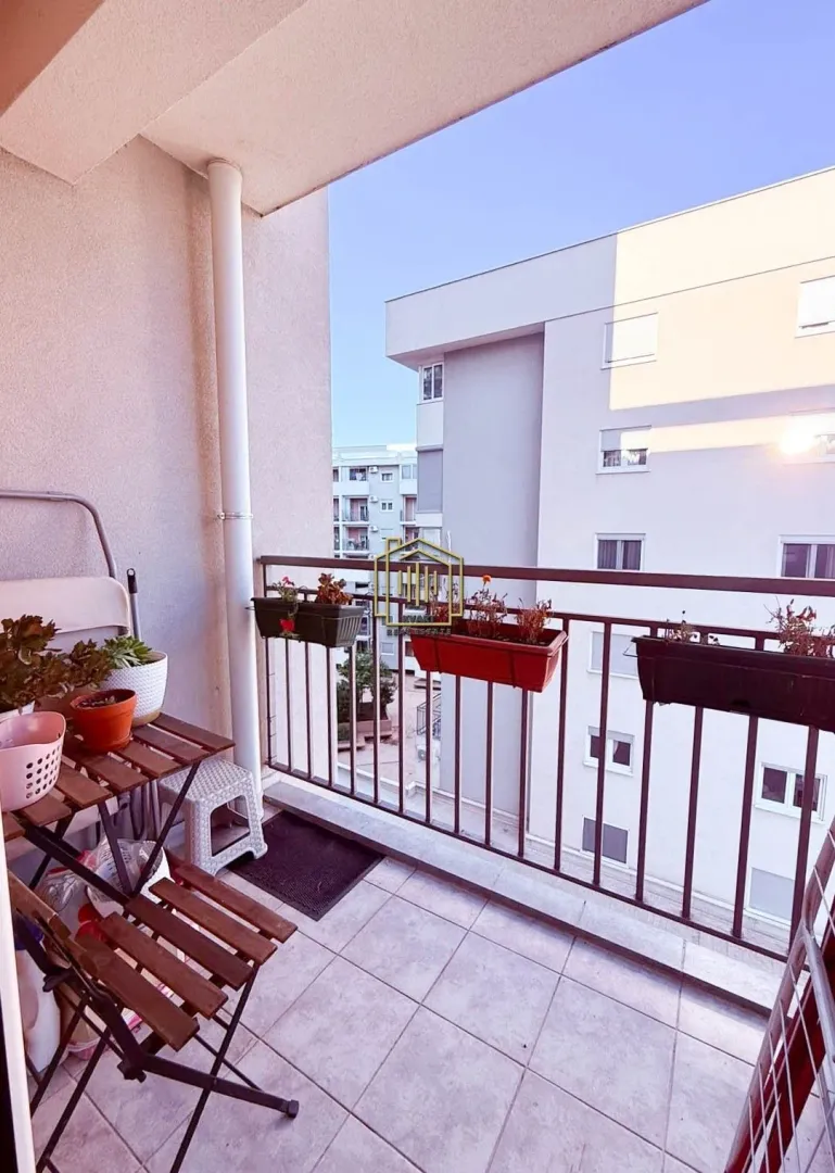 Namtješten balkon sa stolom, stolicama i saksijama sa cvijećem.