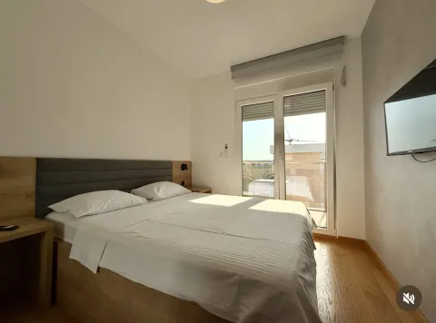 Spavaća soba sa bračnim krevetom, drvenim podom i izlazom na terasu. - image 6