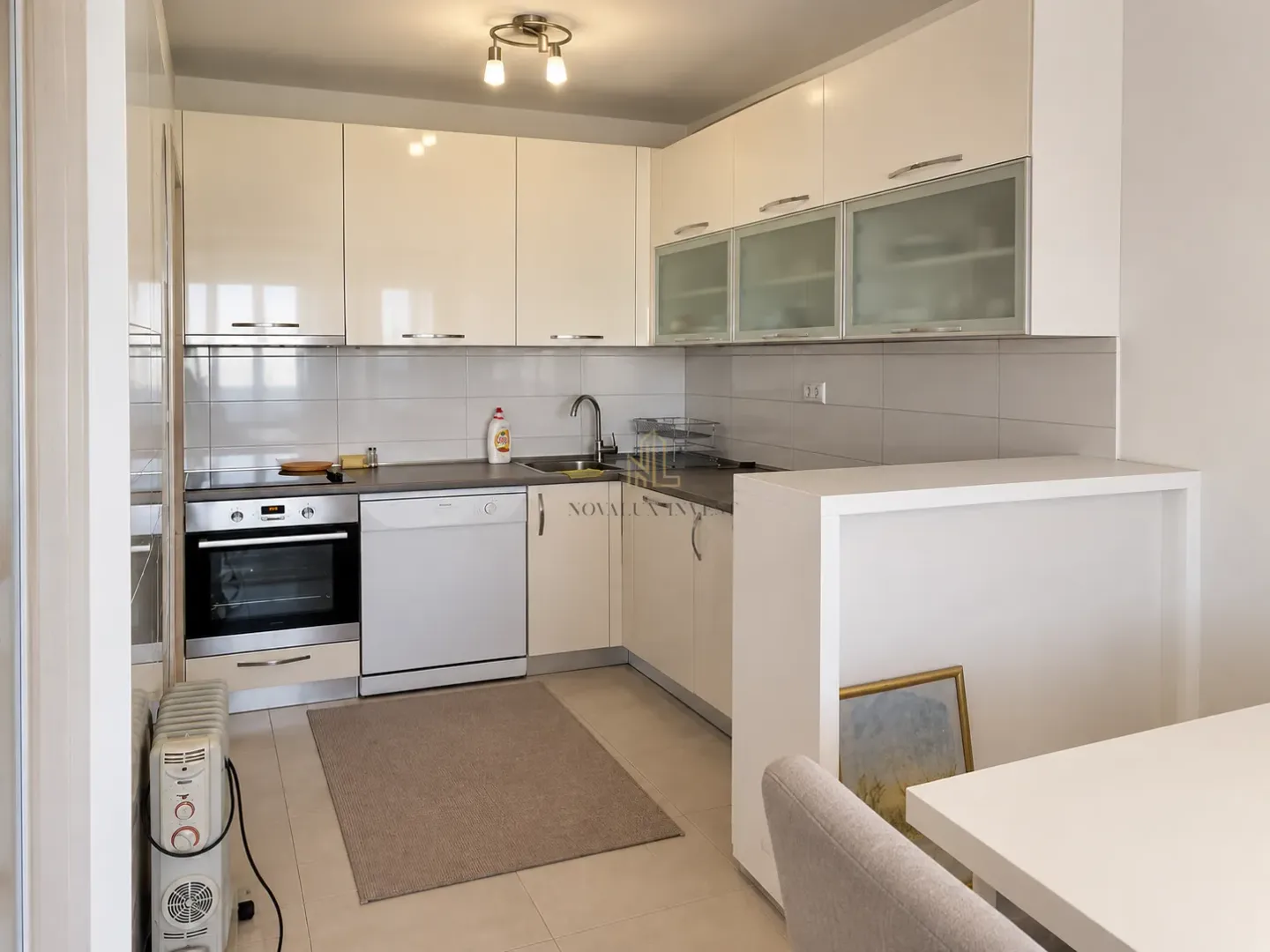 Modern white kitchen with built-in appliances and a dining area.