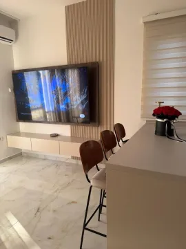 Living room with a TV and a bar counter with bar stools. - image 3