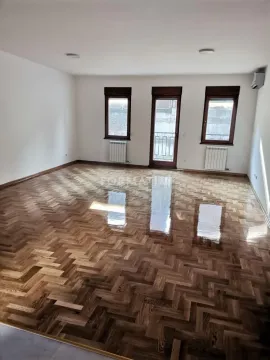 Prazna soba sa lakiranim parketom, prozorima i vratima koja vode na terasu. - image 5
