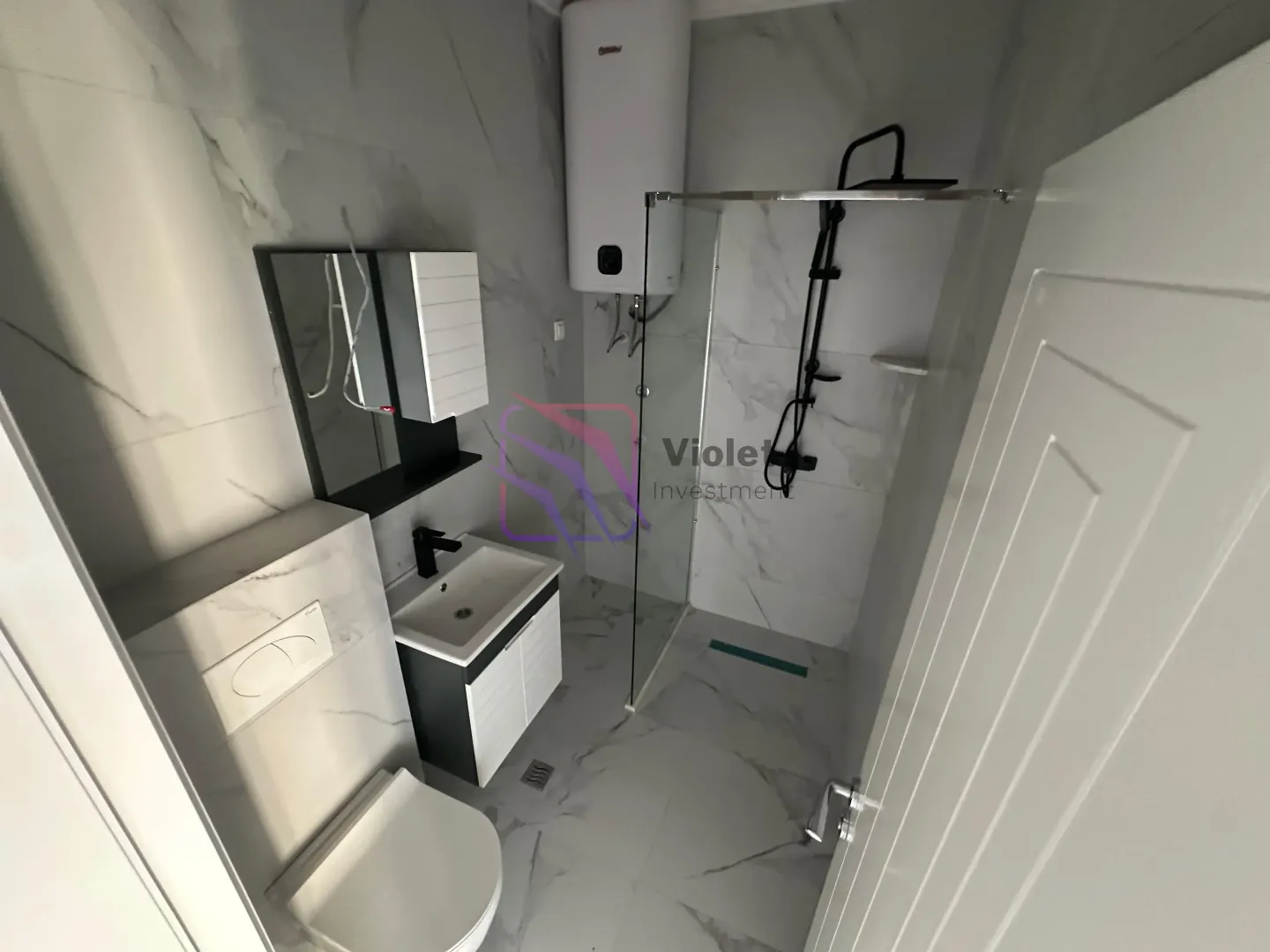 Modern bathroom with a walk-in shower, washbasin, toilet, and water heater.