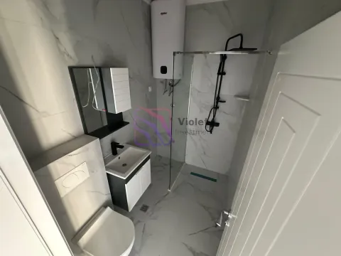 Modern bathroom with a walk-in shower, washbasin, toilet, and water heater. - image 3