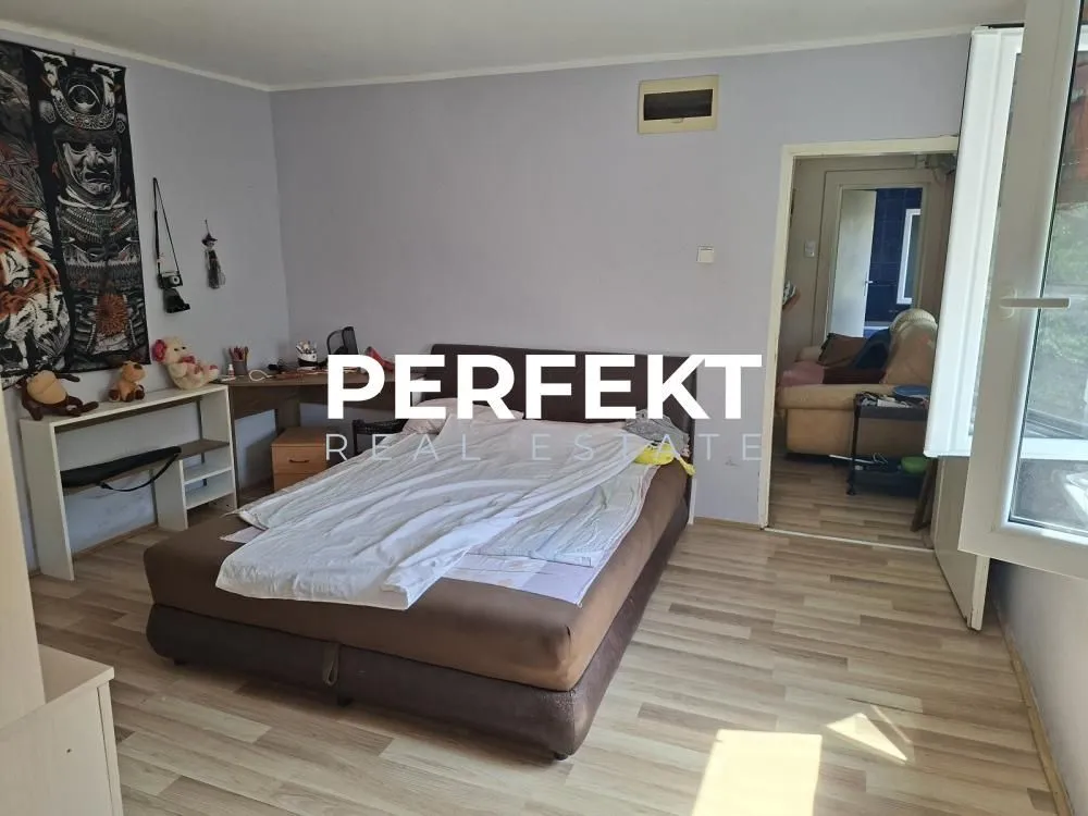 Nameštena spavaća soba sa bračnim krevetom i radnim stolom.