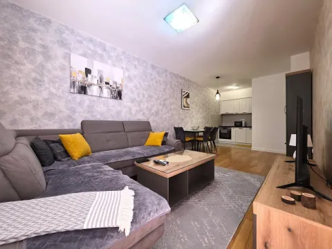 Living room with a corner sofa, coffee table, and TV, overlooking the kitchen and dining area. - image 3