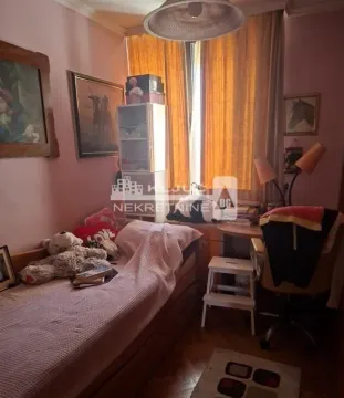 Nameštena spavaća soba sa krevetom, radnim stolom i slikama na zidu. - image 13