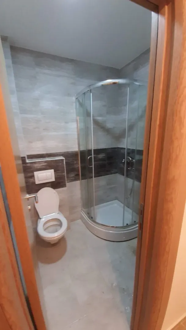 View of the bathroom with a shower cabin and toilet through the open door.