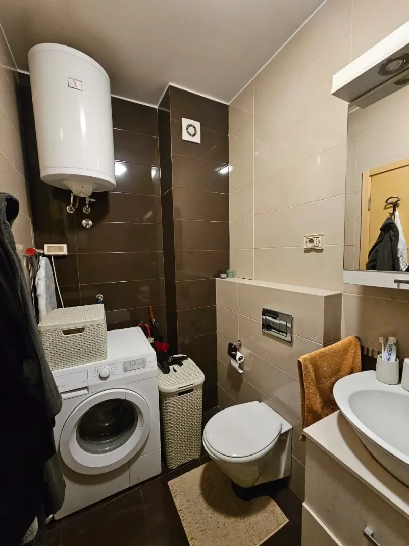 Smaller bathroom with a shower cabin, sink, and toilet.