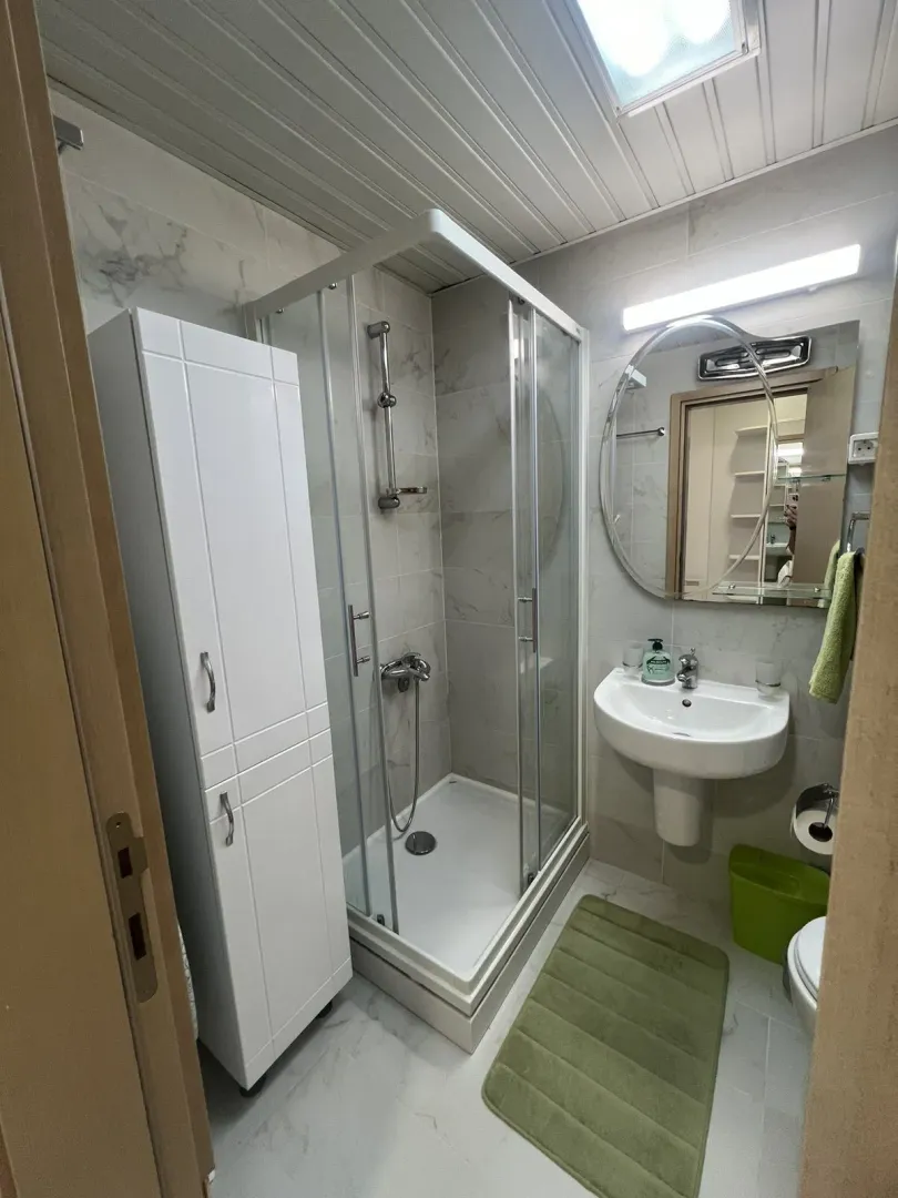 Bright bathroom with a shower cabin, sink, and cabinet.