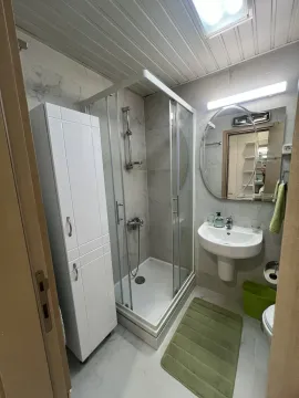 Bright bathroom with a shower cabin, sink, and cabinet. - image 11